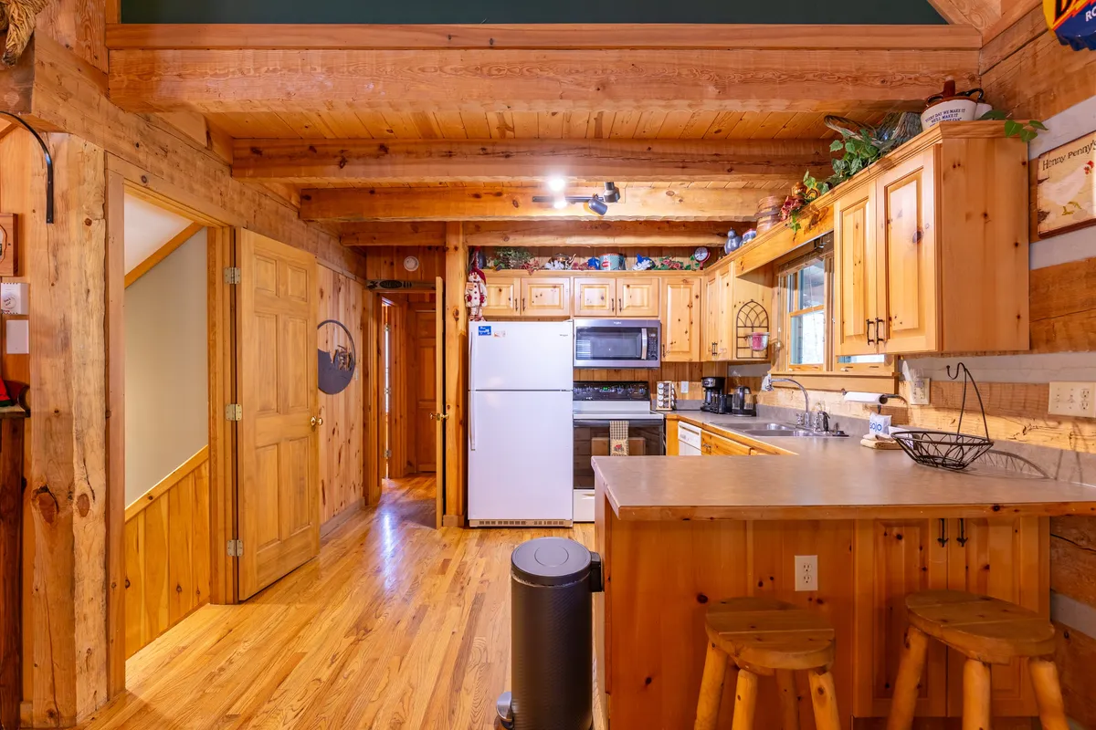 A well-equipped kitchen with wooden cabinetry, ample countertop space, bar stools at a breakfast bar, and modern appliances. The setup is open and inviting, encouraging group cooking and casual dining.