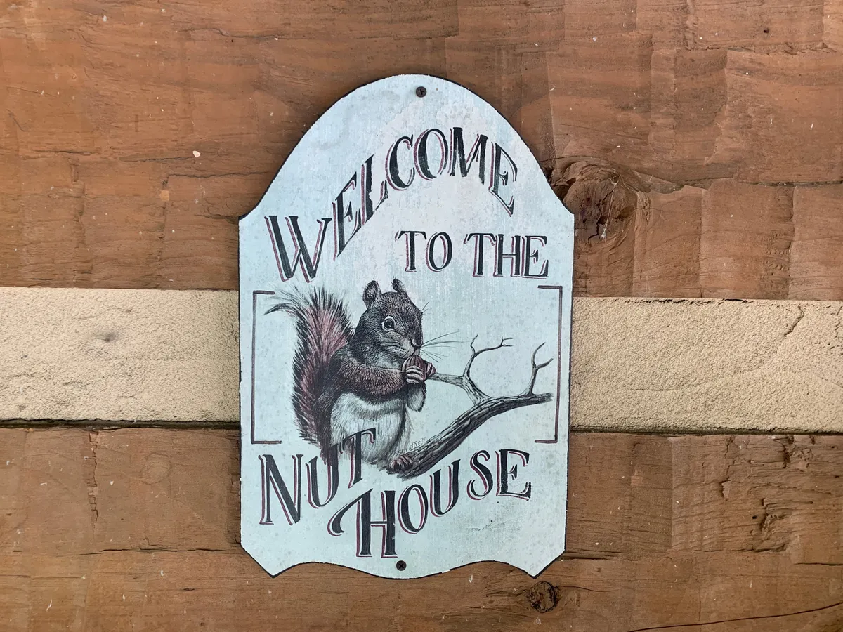A whimsical entry sign featuring a squirrel illustration and playful text. The sign appears welcoming, setting a friendly, pet-loving tone for arriving guests and their furry companions.
